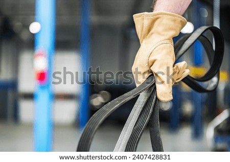 Car Mechanic with a Brand New Serpentine Belt in His Hands. Drive Belt Replacing Theme. Royalty-Free Stock Photo #2407428831
