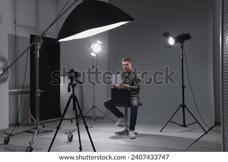 Casting call. Man with script sitting on chair and performing in front of camera in studio Royalty-Free Stock Photo #2407433747