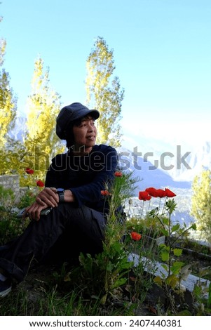 An Asian female tourist enjoy taking a picture with red poppies at a hotel in Hunza Valley in Gilgit-Baltistan region of Pakistan.