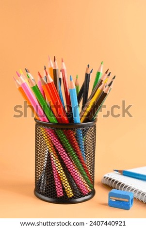 multi color pencils a pencil sharpener and a notebook
