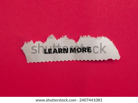 Learn more lettering on ripped paper piece with red background. Conceptual business or education photo. Top view, copy space.