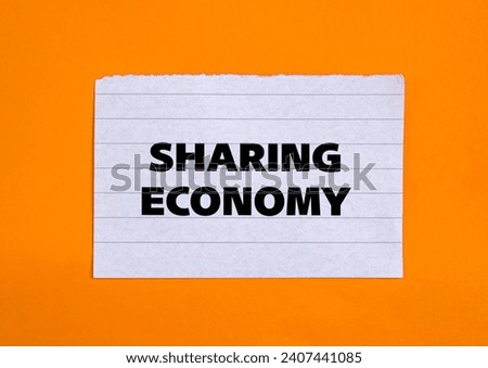 Sharing economy lettering on ripped white paper piece with orange background. Business concept photo. Top view, copy space.