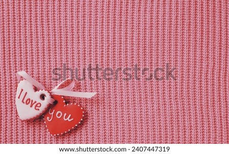 Two gingerbread hearts are tied with a ribbon. Declaration of love on a pink knitted background. Romantic wallpapers