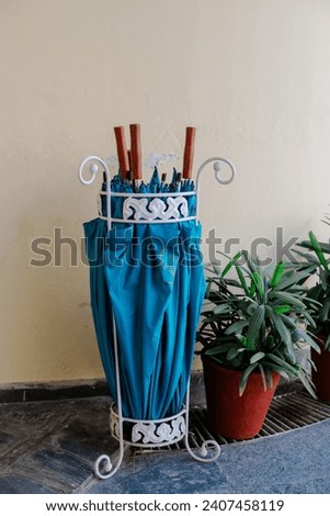 Black and white umbrella stand in special geometric stand against the white wall and wooden stand indoors

