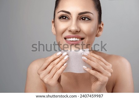 Skin care. Young woman removing oil from face using blotting papers. Photo of beautiful woman with smooth and healthy skin. Beauty concept  Royalty-Free Stock Photo #2407459987