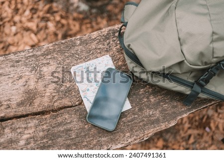 camping backpack, mobile phone, map on floor at the forest. Travel concept. vintage style. High quality photo