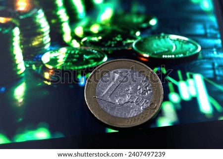 One euro coin on the background of a green stock graph.
