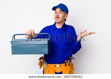 young hispanic plumber feeling puzzled and confused and doubting. toolbox concept