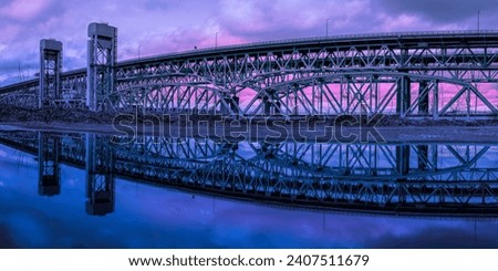 Gold Star Memorial Bridge in New London, Connecticut, the arching landmark suspending bridge over the Thames River, reflected symmetrical shapes over the water at twilight Royalty-Free Stock Photo #2407511679