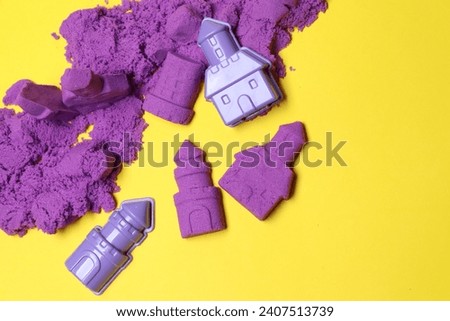 Castle figures made of kinetic sand and plastic toys on yellow background, flat lay. Space for text Royalty-Free Stock Photo #2407513739