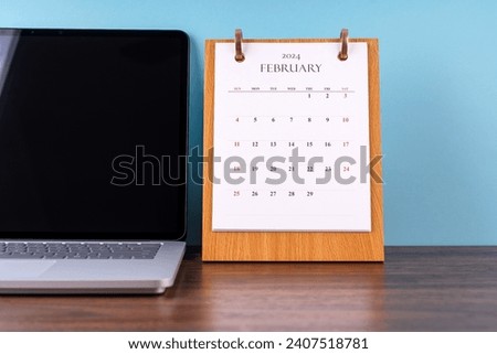 February 2024 desk calendar and laptop Royalty-Free Stock Photo #2407518781