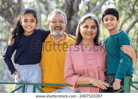 Happy grandparents having fun with grandchildren in park