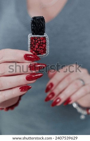 hands with long nails and a bright red and black manicure