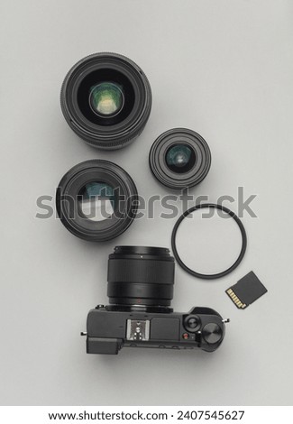 Professional photographer equipment. Modern mirrorless camera with lenses, memory card and light filter on a gray background. Top view. Flat lay