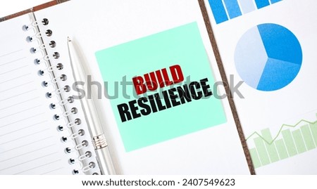 Green card on the white notepad. Text BUILD RESILIENCE. Business concept