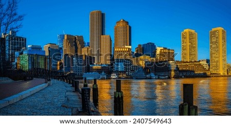 Boston Harbor and Financial District Skyline Panorama with Skyscrapers, Buildings, Boardwalk, and Water Reflections at sunrise against the blue sky in Massachusetts, USA