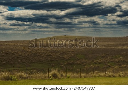 moody skies and rolling hills landscape.