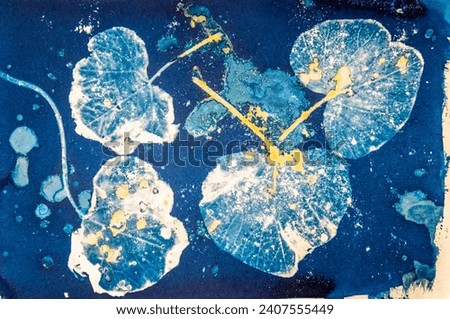 A handmade image of plant leaves using an old photographic process called a Cyanotype mixed with a Turmeric Anthotype process.