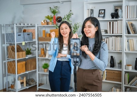Two female salespeople are live-streaming a sale on their mobile phones on TikTok Royalty-Free Stock Photo #2407556505