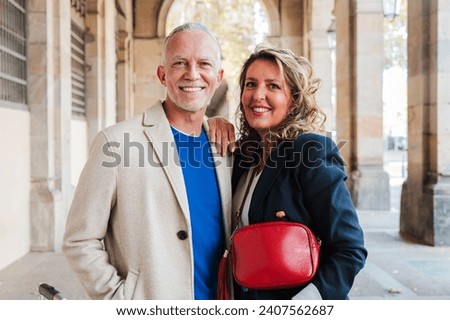 Horizontal portrait of a real mature married couple smiling and looking at camera. Mid adult partners staring front with happy expression. Middle aged wife and husband. Spouse and gray hair man. High Royalty-Free Stock Photo #2407562687