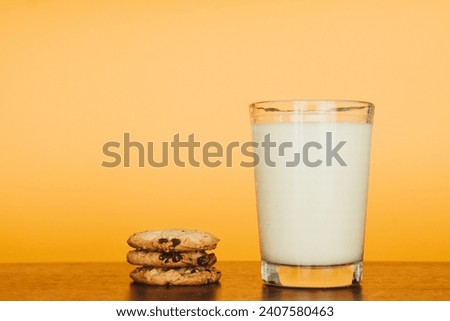 Inviting breakfast scene: cookies and milk on a rustic table with an orange backdrop. Perfect for marketing.