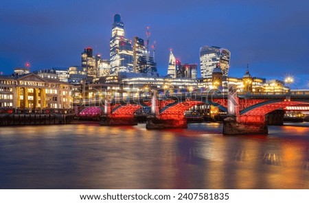 Southwark Bridge in english metropole London spanning over river Thames at evening blue hour twilight with colorful illumination at christmas time. Modern skyline with office towers in the background.