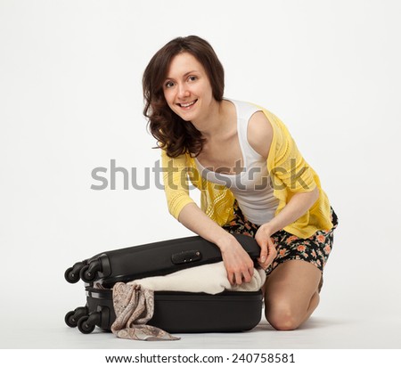 Attractive smiling young woman packing her suitcase