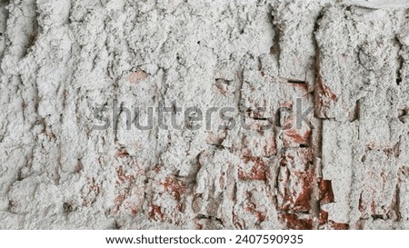 A fragment of an old, abandoned brick wall with plaster damaged by time.