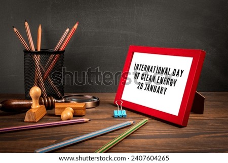 International Day of Clean Energy 26 January. Red picture frame with text on wooden table.