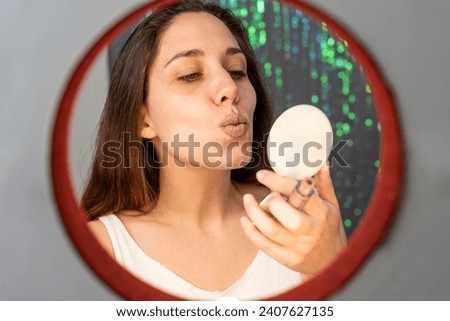 young woman in beauty and makeup center putting on makeup in front of a mirror and cell phone with a ring of light happy painting her lips and cheekbo Royalty-Free Stock Photo #2407627135