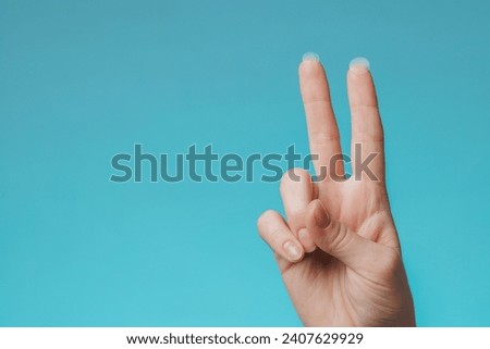 Close-up round acne patch on finger on blue background. Acne patches for treatment of pimple and rosacea close-up. Facial rejuvenation cleansing cosmetology Royalty-Free Stock Photo #2407629929