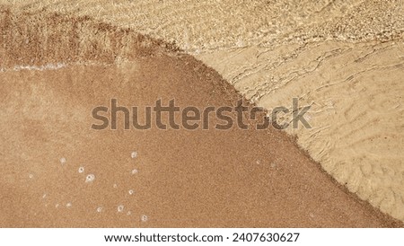 Clear sea water on the golden sand of the coast creating a beautiful curved line. A background suitable for a beach and holiday theme has room for text and products.