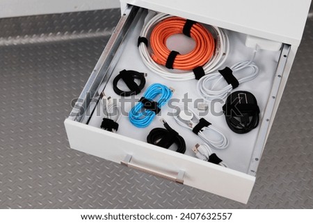 Cables sorted and collected in a drawer of a chest of drawers. Royalty-Free Stock Photo #2407632557