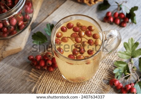 Herbal tea in a glass cup with fresh hawthorn berries Royalty-Free Stock Photo #2407634337