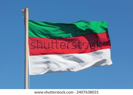 The flag of the German island Heligoland (Helgoland) in the North Sea  flying in the wind with blue sky. The flag is a triband with the colors green, red and white. Royalty-Free Stock Photo #2407638031