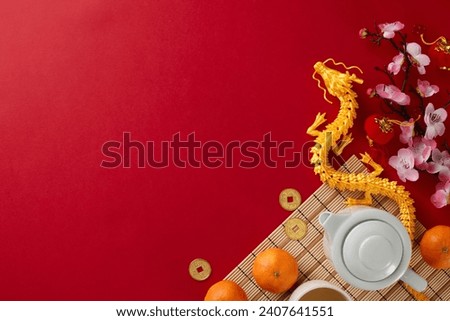 Embracing the traditional chinese New Year tea ceremony. Top view shot of teapot, cups of tea, tangerines, gold dragon, traditional chinese decor on red background with advert space