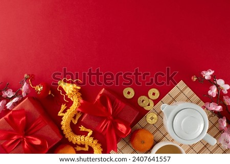 Marking chinese New Year with a tea ceremony celebration. Top view flat lay of teapot, cup of tea, tangerines, gold dragon, gift boxes, traditional chinese decor on red background with advert space