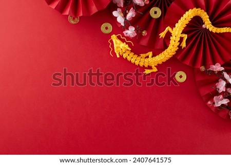 Setting the stage for a festive Lunar New Year 2024. Top view photo of gold dragon, folding fans, traditional coins, sakura bloom on red background with advert zone Royalty-Free Stock Photo #2407641575