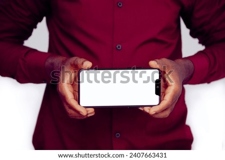 Black man holding and showing smartphone with blank screen in landscape mode isolated white background