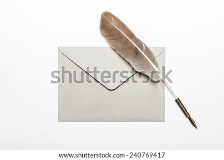 A feather quill pen, envelope, isolated white at the studio.