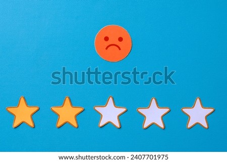 Two star rating with sad emoticon on blue background. Negative feedback concept.