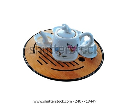 In the picture is a white tea set with a large bowl for hot tea decorated with floral patterns. Next to the bowl are four small white cups for pouring hot tea with the fragrant aroma of tea leaves and