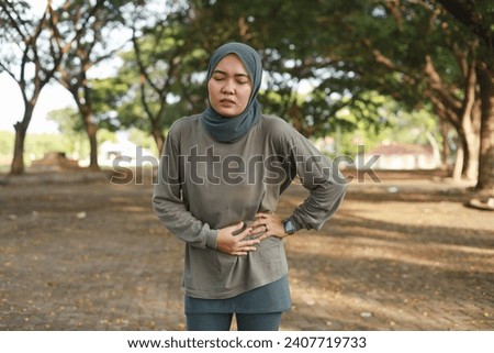Side stitch - asian muslim woman runner side cramps after running Royalty-Free Stock Photo #2407719733