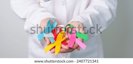 World cancer day, February 4. Doctor holding blue, red, green, white, pink, blue and yellow ribbons for supporting people living and illness. Healthcare and Autism awareness day concept Royalty-Free Stock Photo #2407721341