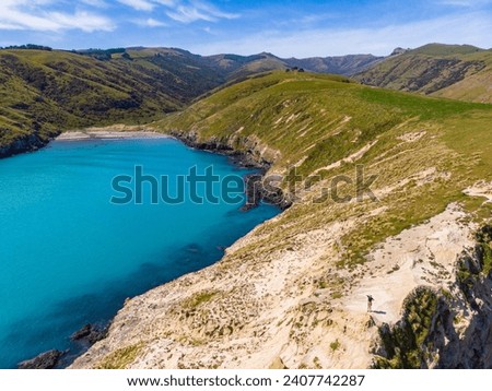 aerial panorama of beautiful tumbledown bay at banks peninsula near christchurch, new zealand south island; little beach in a bay surrounded by mountains, cliffs and turquois ocean