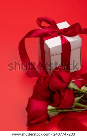 Valentines day card with gift box and rose flowers. On red background with space for your greetings
