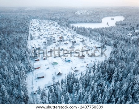 Aerial view of a small settlement in the forest near the lake during winter. A small village in cold weather. Royalty-Free Stock Photo #2407750339