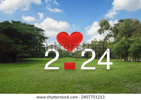 Red fabric heart love air balloon with 2024 white text on green grass and trees in public park, Happy valentines day 2024 cover concept