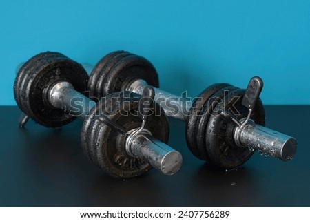 A pair of wet rusty dumbbells indoors on a table. close-up. blue background