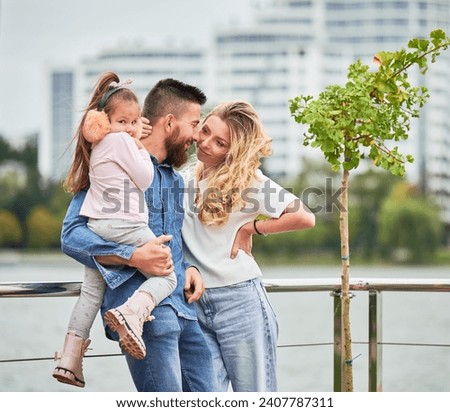 Man and woman with child outdoors. Father holding adorable child while spending time with family in new urban district.